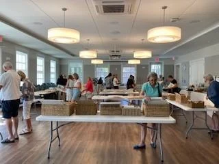 Visitors browsing tables at an art show in the main hall